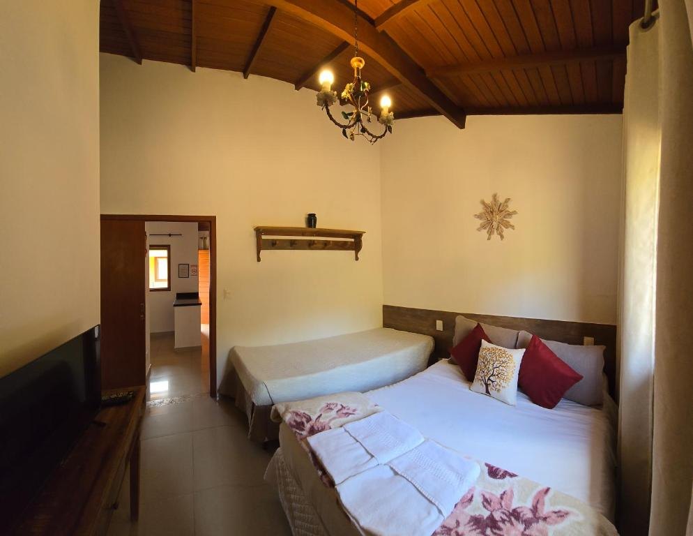 Quarto com cama de casal, cama de solteiro e teto de madeira