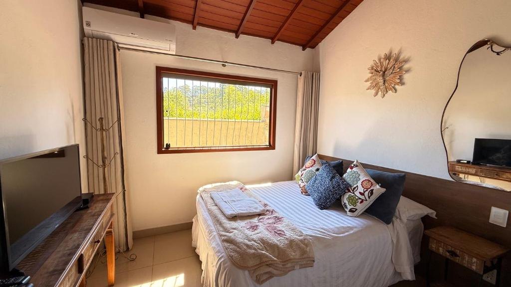Quarto com cama de casal, janela para a mata e ar-condicionado